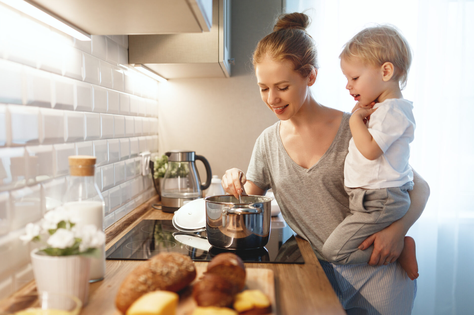 preparation of family breakfast. mother and baby son cook porridge in morning